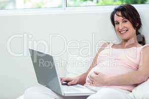 Pregnant woman relaxing with her laptop