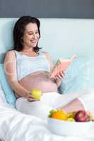 Pregnant woman eating and reading book