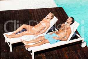 Peaceful couple sunbathing on deck chairs