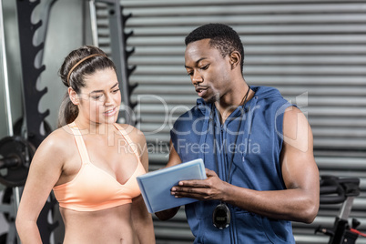 Athletic woman and trainer looking at tablet