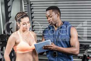 Athletic woman and trainer looking at tablet