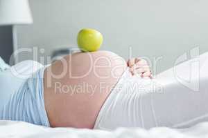 Pregnant woman with apple on belly