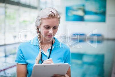 Pretty trainer writing on clipboard