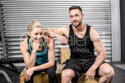 Fit couple sitting on wooden box