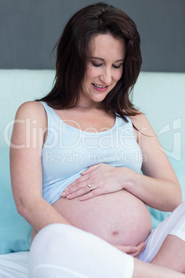 Pregnant woman sitting on bed