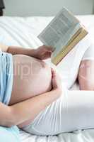 Pregnant woman on bed reading a book