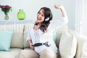Pregnant woman holding headphone on belly