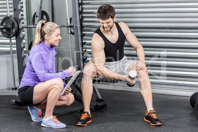 Female trainer assisting man with dumbbells