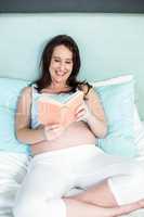 Pregnant woman on bed reading a book