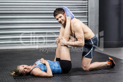 Male trainer assisting woman with sit ups