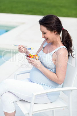 Smiling pregnant woman eating fruit