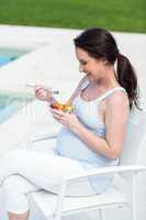 Smiling pregnant woman eating fruit