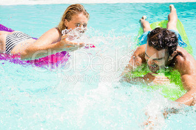 Happy couple with lilos splashing