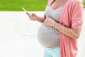 Pregnant woman touching her belly and texting