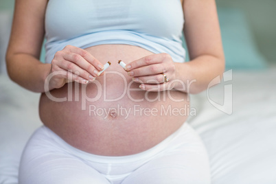 Pregnant woman cutting a cigarette in two