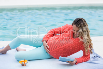 Pregnant woman relaxing outside and using tablet