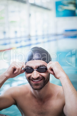 Smiling man wearing swim cap and goggles