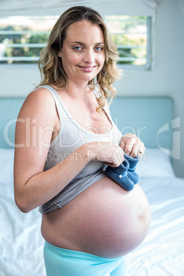 Pregnant woman with knitted slippers on her belly