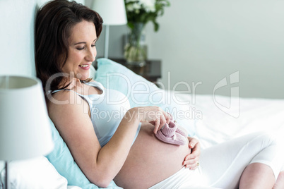 Pregnant woman with knitted slippers on her belly