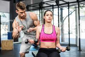 Athletic woman working out helped by trainer man