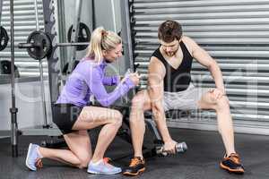 Female trainer assisting man with dumbbells