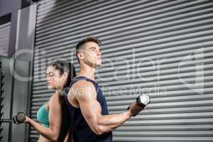 Fit people lifting dumbbells back to back