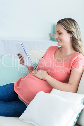 Pregnant woman writing on notepad