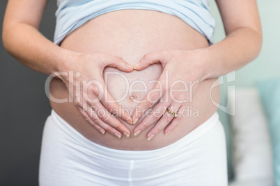 Pregnant woman doing a heart with her hand on her belly