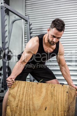 Fit man moving wooden box