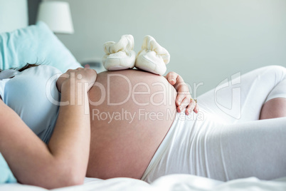 Pregnant woman with baby shoes on belly