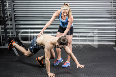 Woman trainer assisting man