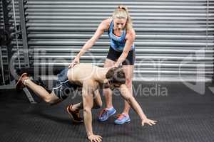 Woman trainer assisting man