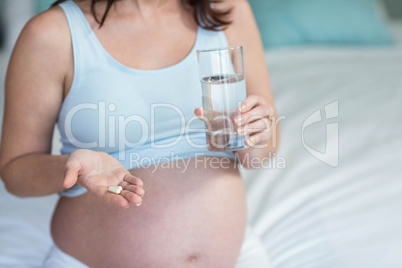 Pregnant woman taking a pill with water