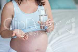 Pregnant woman taking a pill with water