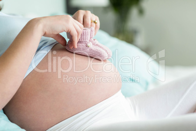 Pregnant woman with knitted slippers on her belly