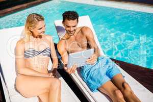 Couple using tablet on deckchairs