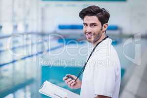 Handsome trainer holding stopwatch and reading clipboard