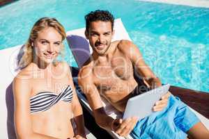 Couple using tablet on deckchairs