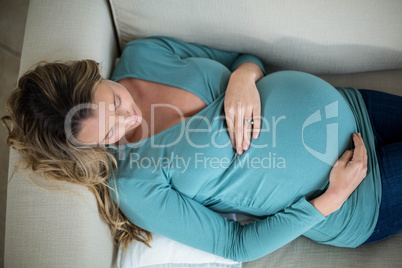 Pregnant woman touching her belly lying on the couch