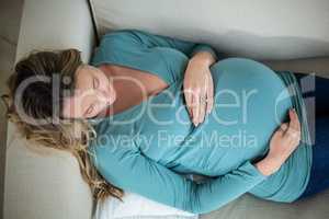 Pregnant woman touching her belly lying on the couch