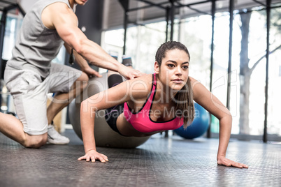 Male trainer assisting woman with push ups