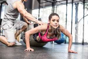 Male trainer assisting woman with push ups