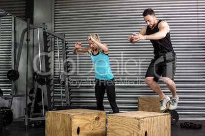Couple doing box jumps in gym