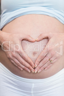 Pregnant woman doing a heart with her hand on her belly