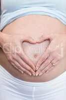Pregnant woman doing a heart with her hand on her belly