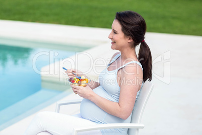 Smiling pregnant woman eating fruit