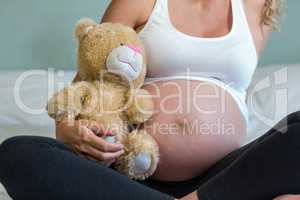 Pregnant woman sitting with a teddy bear