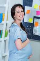 Smiling pregnant woman touching her belly