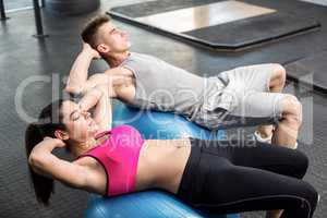 Fit couple doing abdominal crunches on fitness ball