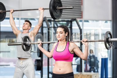 Fit couple lifting barbell